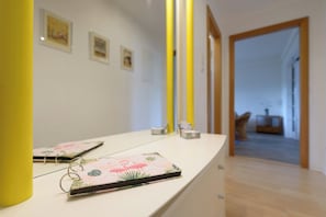 Un couloir avec un comptoir blanc, un miroir et une porte donnant sur une autre pièce.