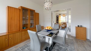 Un comedor con un aparador de madera, una mesa con un cuenco de fruta y una araña.