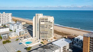 Un hotel sulla costa con piscina, vista sulla spiaggia e diversi edifici.