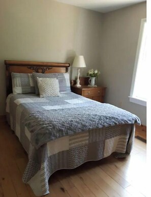 Cozy retreat with a large bed, bedside table, and a vase with flowers.