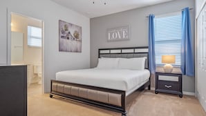 A bedroom with a bed, a nightstand, a ceiling fan, a wall-mounted artwork, and a window with curtains. - Arcade, Caribbean Pool Area, Foosball, Waterpark, 15 mins to Disney: The Springs (Davenport)