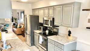 A modern kitchen with stainless steel appliances, grey cabinets, and a marble countertop.
