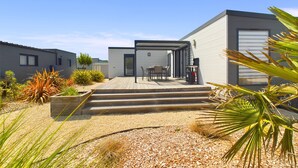 A modern house with a patio, outdoor seating, and a small garden.