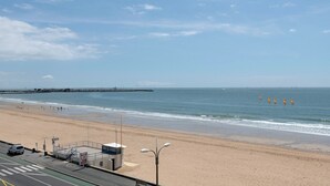 A beach with a road and a building with a blue roof. - 50m from the beach, seaview flat for 5 (Pornichet)