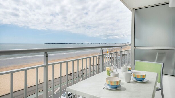 A balcony with a view of the beach and ocean, a table with bowls and a pitcher, and a chair. - 50m from the beach, seaview flat for 5 (Pornichet)