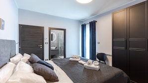 A modern hotel room with a large bed, a wardrobe, a bathroom with a mirror, and a view of the outside. - Beautiful Villa Gallova (Labin)