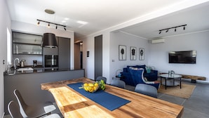 A modern kitchen with a built-in oven and a dining area with a wooden table and chairs. - Beautiful Villa Gallova (Labin)