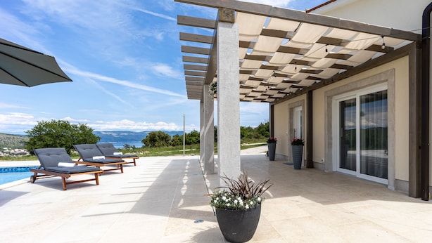 A poolside area with lounge chairs, a pergola with a canopy, and a potted plant. - Beautiful Villa Gallova (Labin)