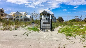 Ein verschlossener Eingang zu einem Anwesen am Strand, mit Häusern im Hintergrund.