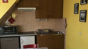 Cocina compacta con armarios de madera, microondas, tostadora y lavamanos.