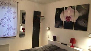 Un dormitorio con cama, cómoda, espejo y decoración en la pared.