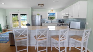 A kitchen with white cabinets, a stainless steel refrigerator, a sink, and a window with a view of the outdoors. - CABANA DEL SOL IS A 2BD/2BA GULF FRONT W/AMAZING VIEWS, 2 SCREEN PORCHES! (Port Saint Joe)