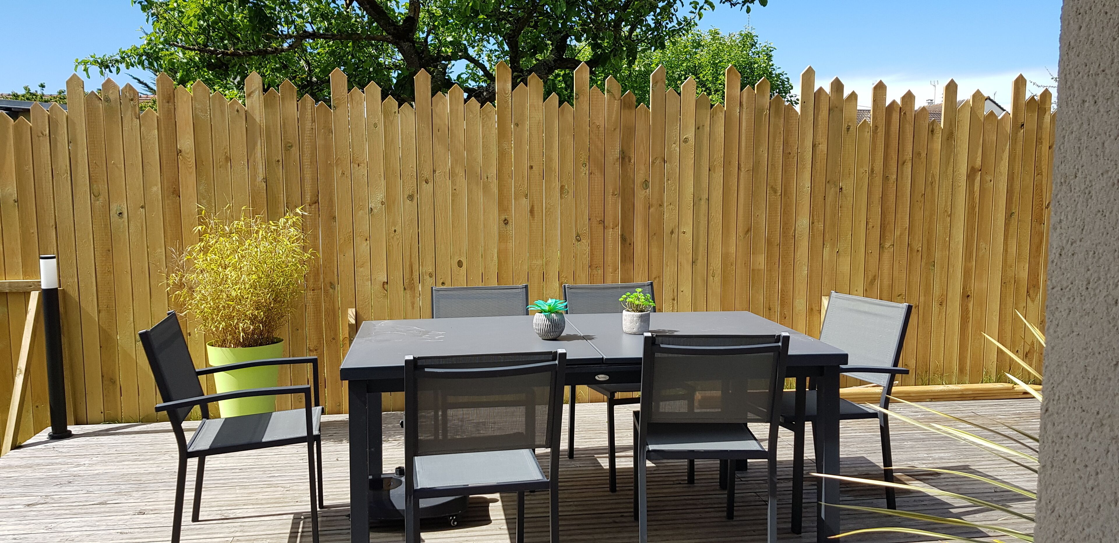 A wooden deck with a table and chairs, surrounded by a wooden fence.