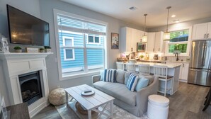 A modern kitchen with white cabinets, a stainless steel refrigerator, and a dining area with a white island. - Beachwalk Resort Cottage with Pool Access/Golf Cart (Michigan City)