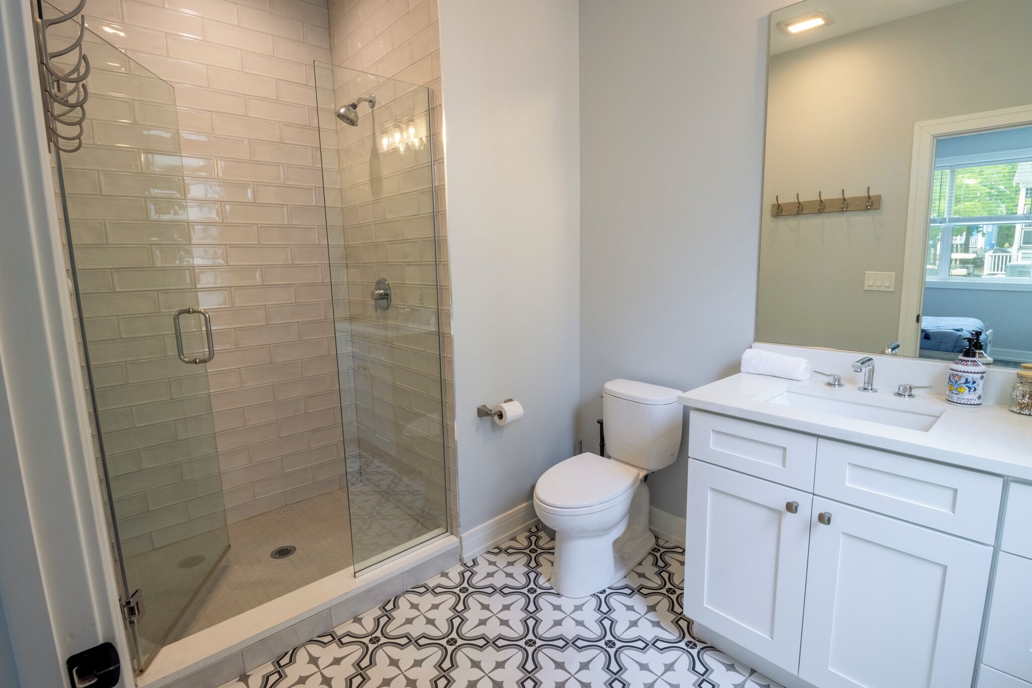 A bathroom with a glass-enclosed shower, a toilet, and a sink with a mirror above it.
