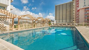A swimming pool with a clear blue water, surrounded by a wooden fence and lounge chairs. - Golf Course & Mountain Views at the Island Colony Amazing Building Amenities (Honolulu)