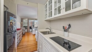 A modern kitchen with white cabinets, a stainless steel sink, and a built-in stove. - Golf Course & Mountain Views at the Island Colony Amazing Building Amenities (Honolulu)