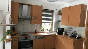 Eine moderne Küche mit Holzausstattung, einer Edelstahl-Dunstabzugshaube, einem eingebauten Backofen und einer Kaffeemaschine.