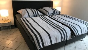 Ein Bett mit schwarz-weiß gestreifter Bettwäsche, zwei Nachttische mit Lampen und ein dunkles Kopfteil.