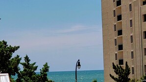 A coastal view with a street lamp, a building with multiple windows, and a clear sky.