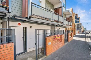 Un edificio de apartamentos moderno con entrada protegida, un balcón y un muro de ladrillo con una escultura decorativa de un animal.