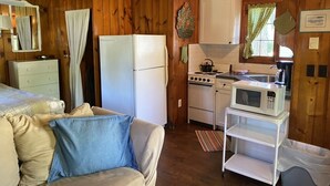 A compact kitchen with a refrigerator, stove, microwave, and a small sink.