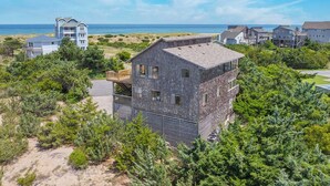 A coastal house with a stone facade, a balcony, and a view of the sea.
