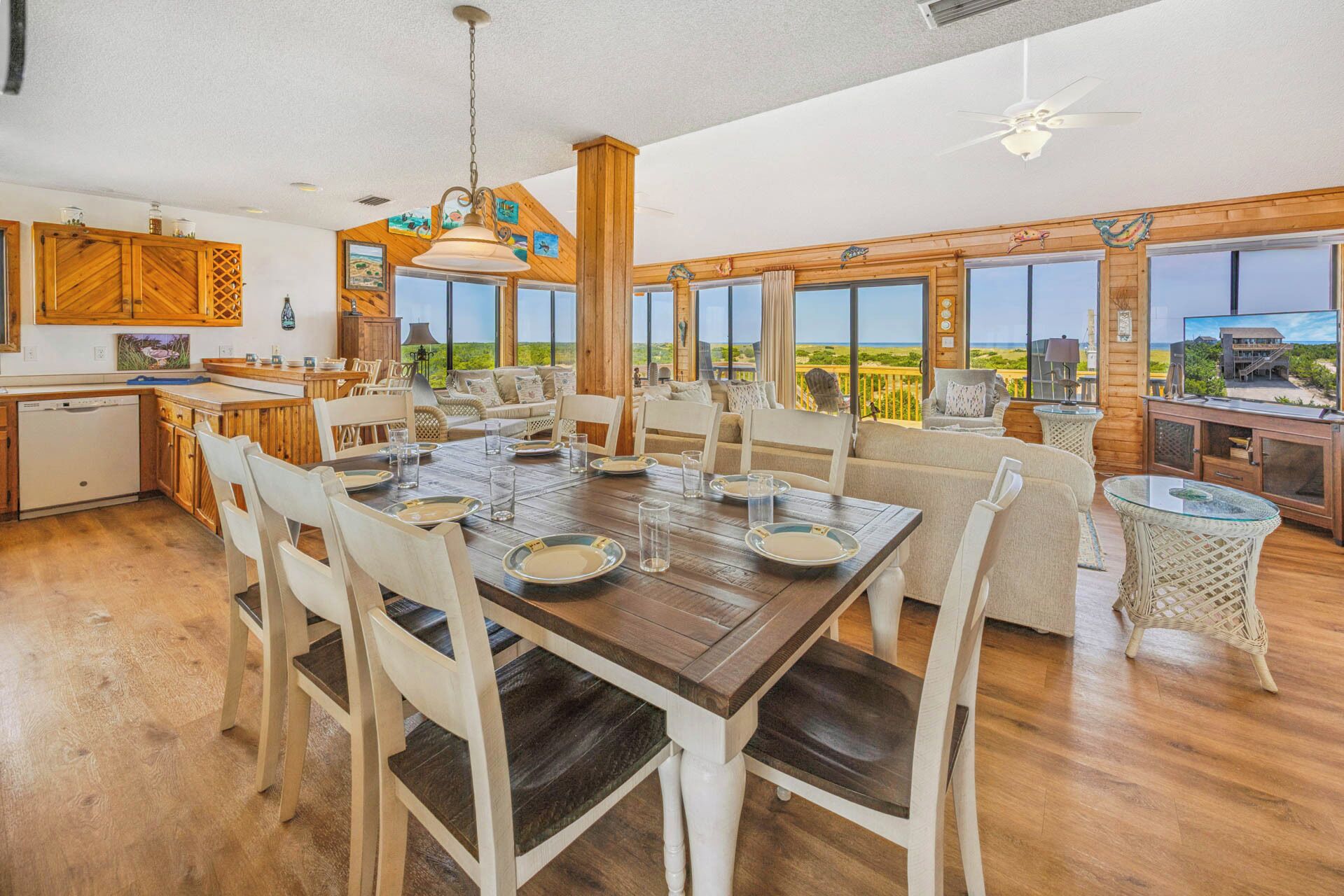 A spacious dining area with a wooden table set for six, surrounded by white chairs.