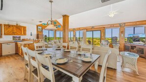 A spacious dining area with a wooden table set for six, surrounded by white chairs.