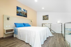 Ein Schlafzimmer mit Bett, Kopfstütze, Nachttisch, Regal und zwei Bildern an der Wand.