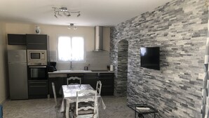 A modern kitchen with a dining area, featuring a built-in oven, microwave, and a large window.