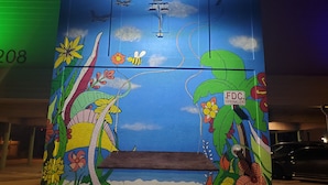 Une fresque colorée représentant une scène de plage avec une planche de surf, un avion et des fleurs.