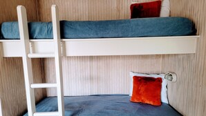 Un lit superposé avec une échelle, deux oreillers et une tête de lit dotée d’un luminaire.