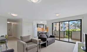 Eine moderne Wohnung mit Wohnzimmer, Essbereich, Küchenzeile und einem Balkon mit Blick auf die Stadt.