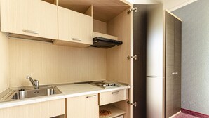 Una cucina compatta con lavello, fornello, microonde e piccolo forno.