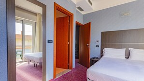 Una camera d'albergo con un letto grande, una scrivania, una sedia e un balcone con una poltrona verde.