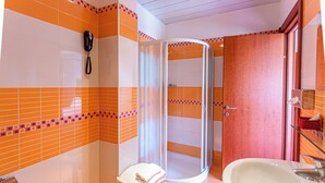 Un bagno con box doccia in vetro, lavandino e telefono.