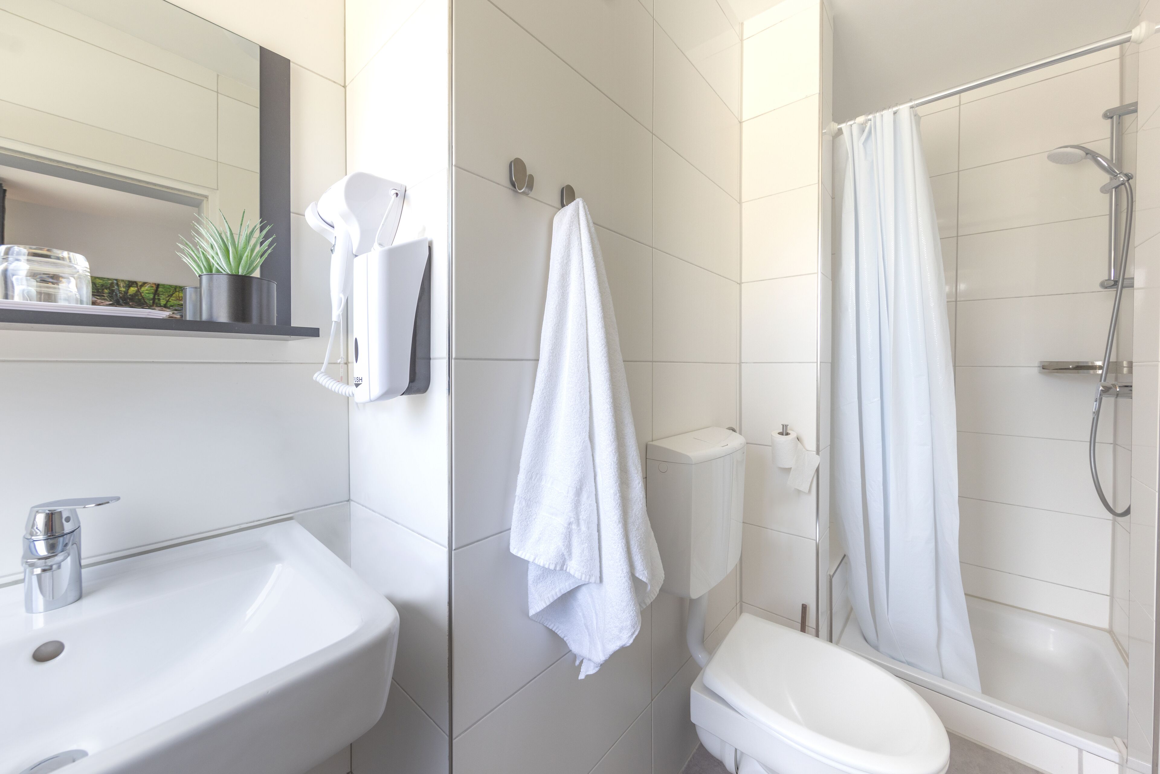 Un baño moderno con lavamanos, inodoro y ducha.