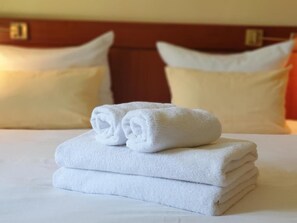 A neatly made bed with white towels folded on top, a wooden headboard, and two pillows. - dreams Beckum (Beckum)