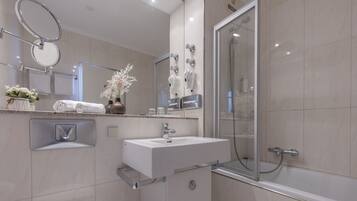 A modern bathroom with a large mirror, a sink, a shower, and a toilet.