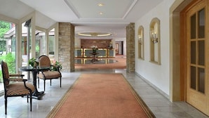 A hotel lobby with a reception desk, a round table with chairs, and a carpeted walkway. - dreams Beckum (Beckum)