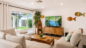 A living room with a sofa, coffee table, TV, wooden cabinet, and decorative fish wall art.