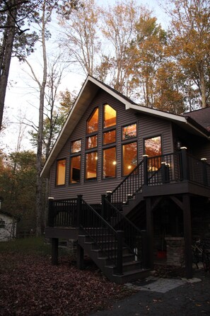 A two-story cabin with large windows, a balcony, and a staircase.
