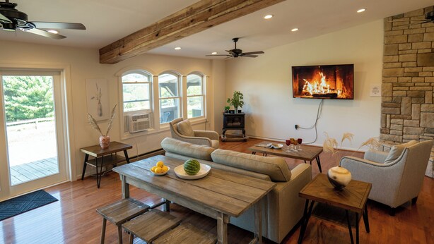 Ein geräumiges Wohnzimmer mit Holzbalkendecke, Kamin und Wand-Fernseher.