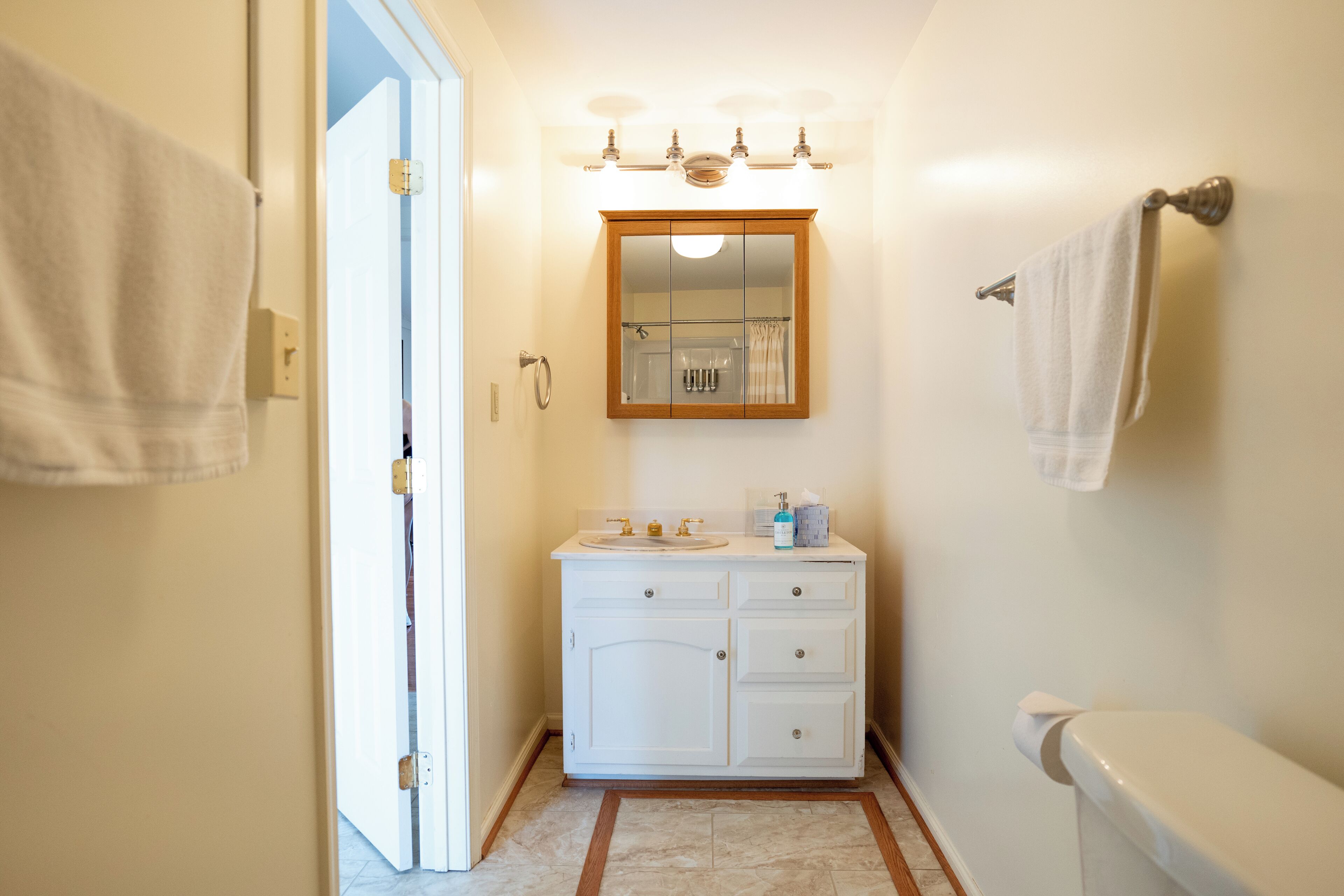 Une salle de bain avec un meuble-lavabo blanc, un miroir et des toilettes.