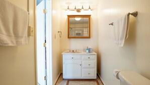 Ein Badezimmer mit weißem Waschtisch, einem Spiegel und einer Toilette.