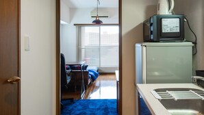 Una cocina compacta con un lavamanos, un microondas y una tetera en la encimera.