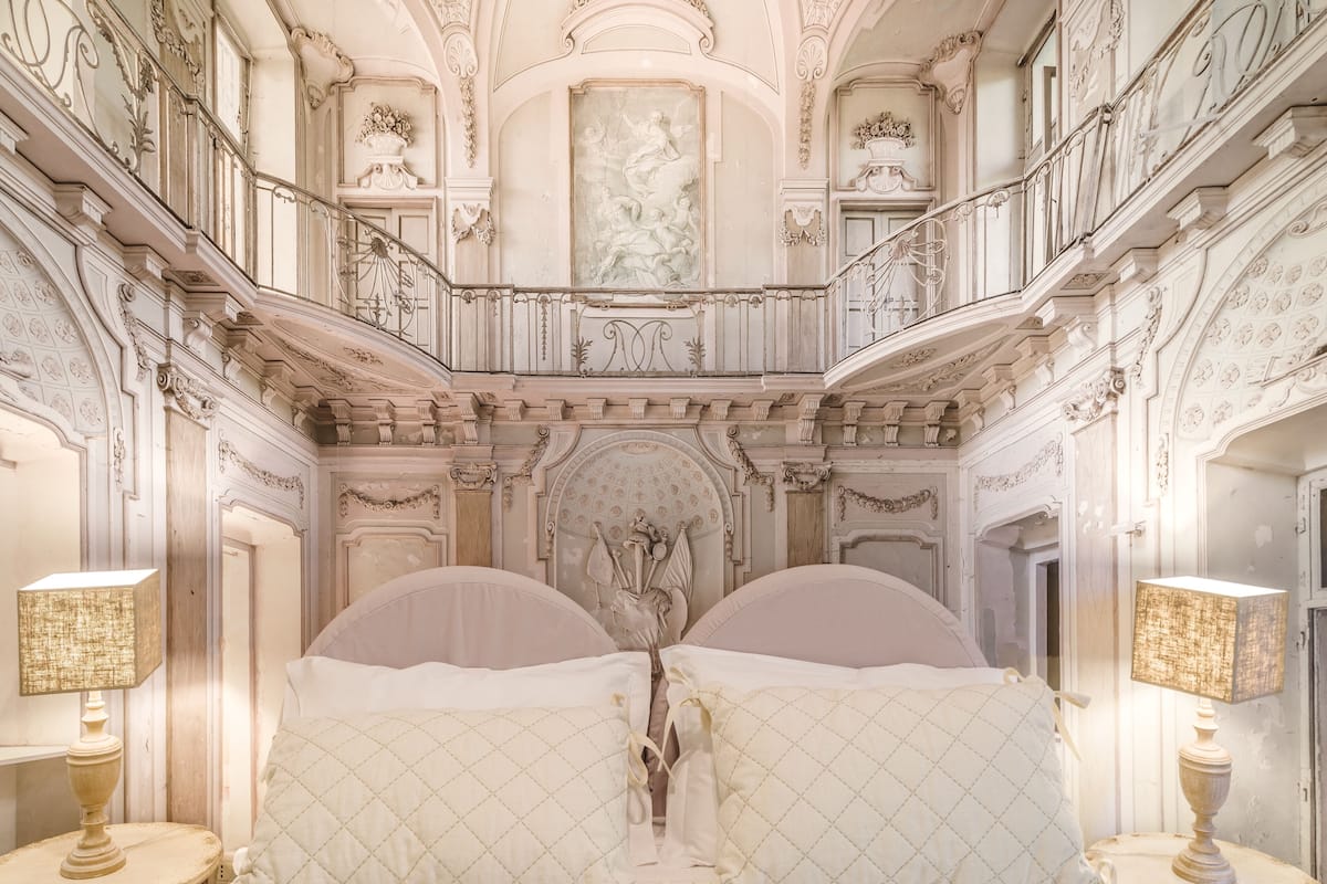 Ein großzügiger Raum mit einem großen Bett, einer verzierten Decke und einem Balkon mit Geländer.