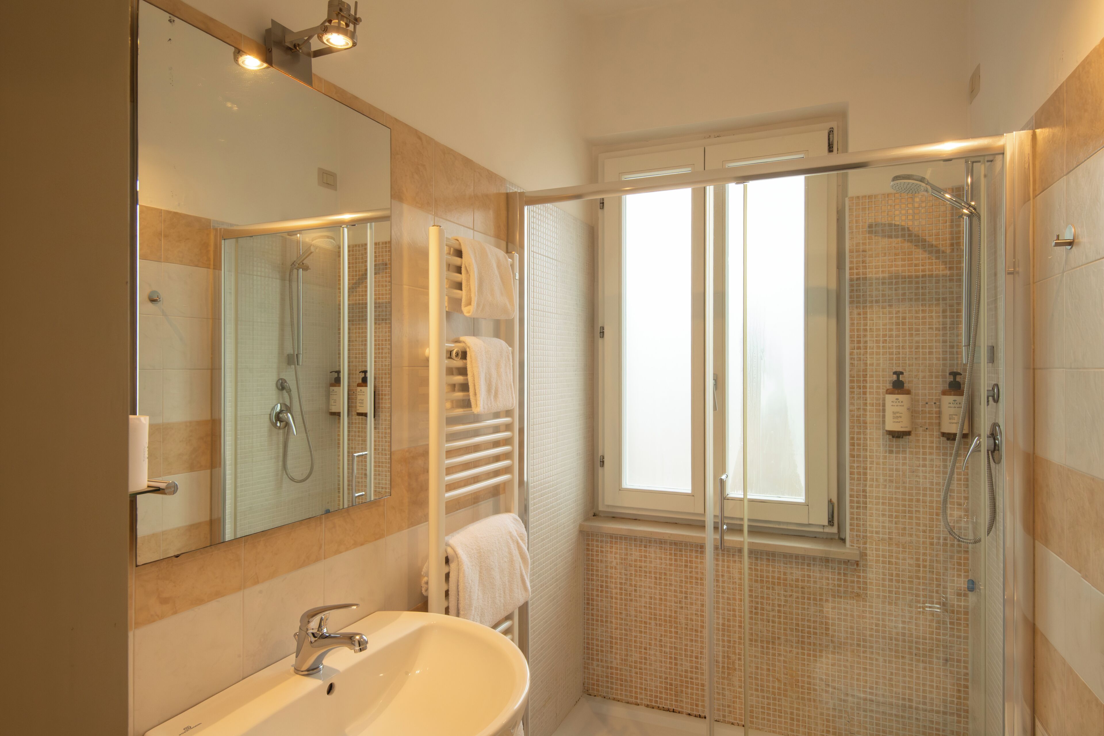 Ein modernes Badezimmer mit einer Duschkabine, einem großen Spiegel und einer Badewanne.