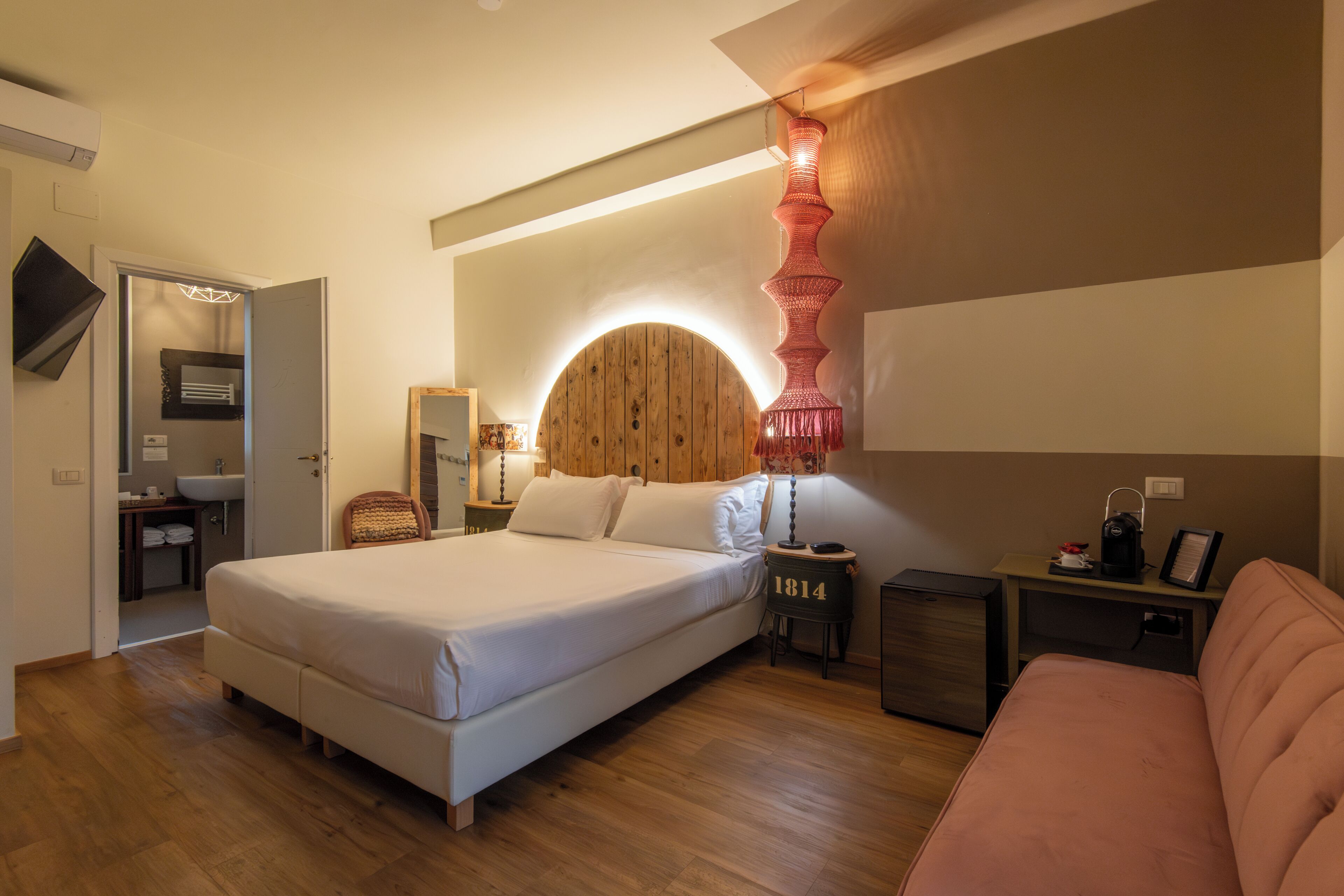 Un dormitorio moderno con una cama grande, mesitas de noche, un cabecero de madera y un escritorio pequeño con una silla.